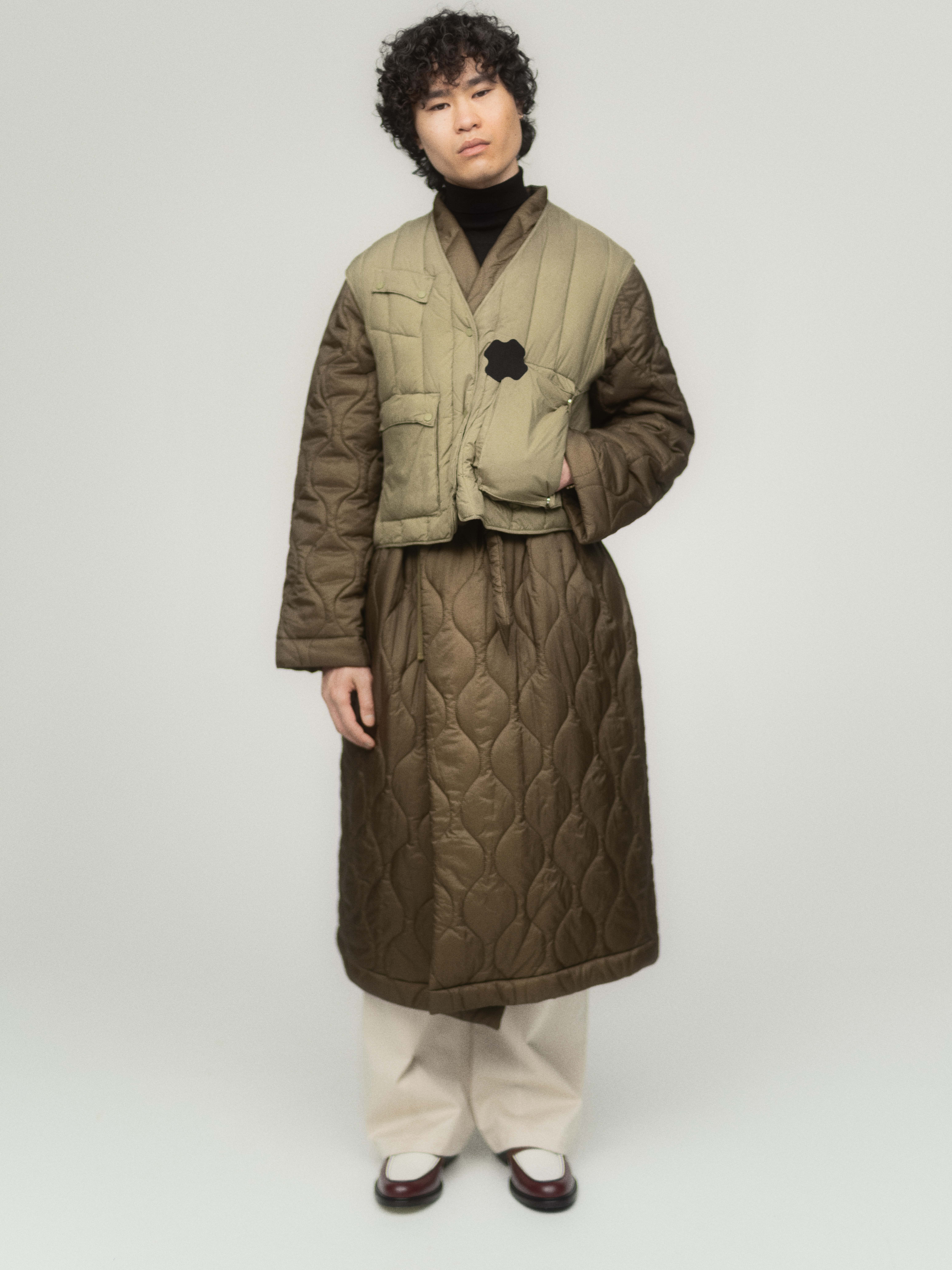 Mies jolla on toppatakki ja toppaliivi, jossa on vaatelaastari 