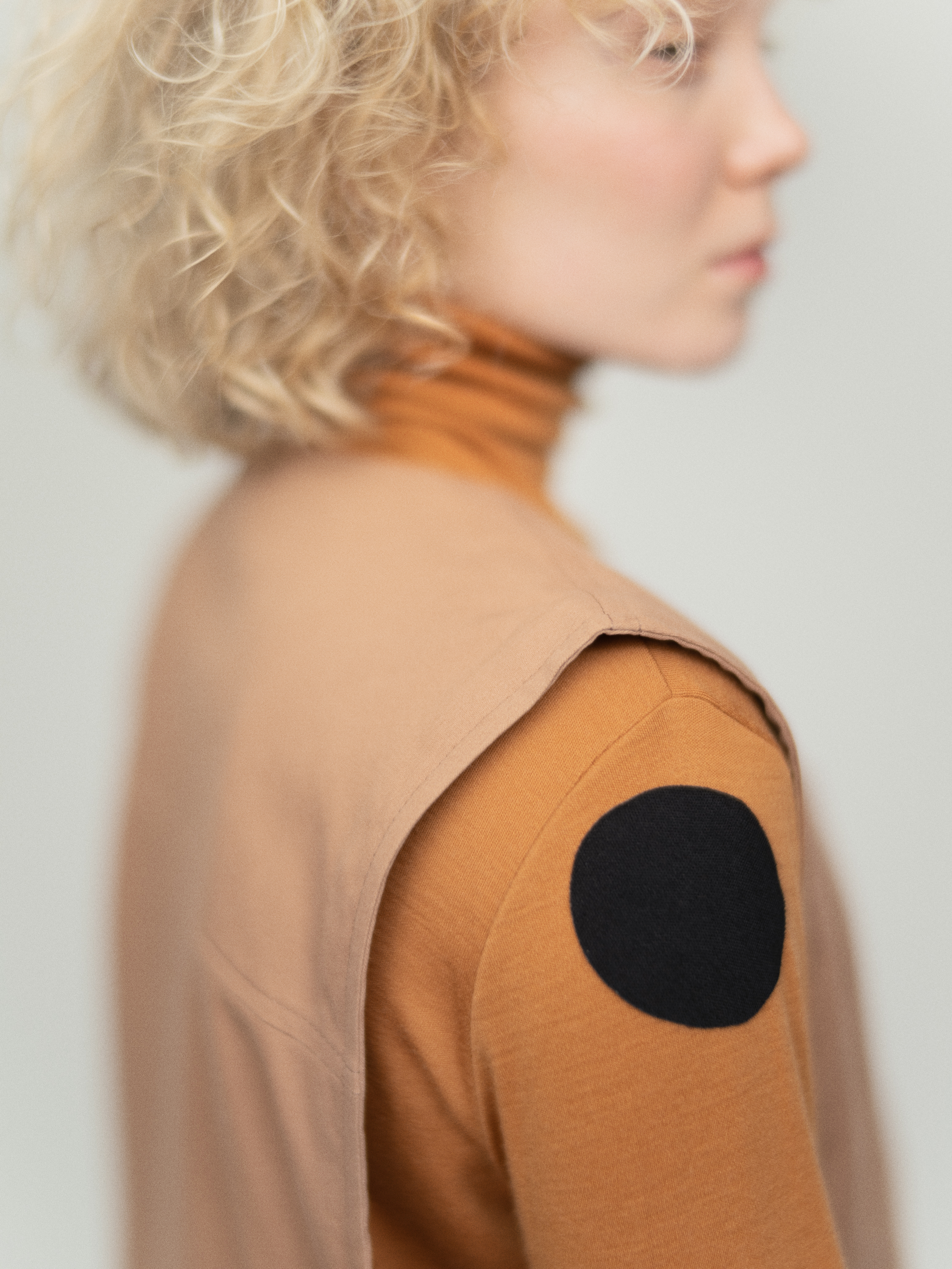 Nainen jolla on pitkähihainen poolopaita, jossa on hihassa vaatelaastari