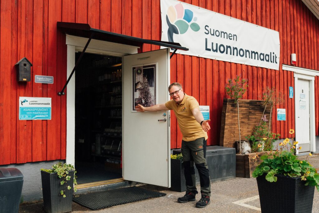 Suomen Luonnonmaalien työntekijä pitää kaupan ovea auki.